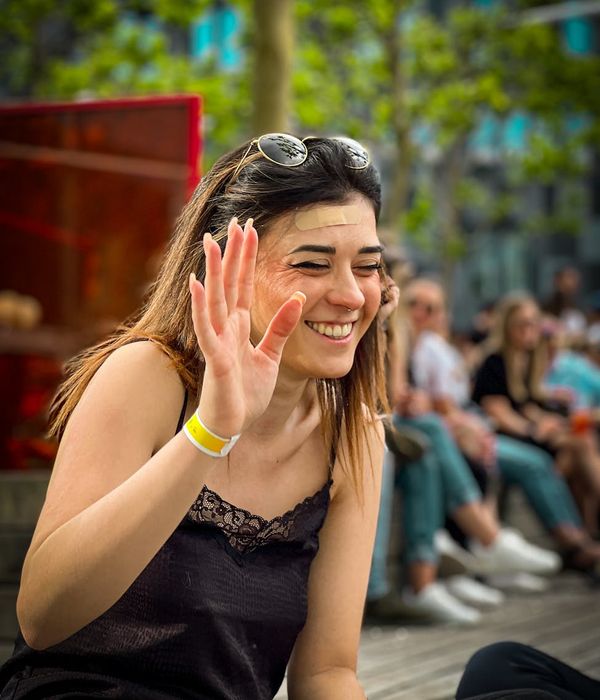 Smiling woman in a relaxed seated yoga pose in a park.